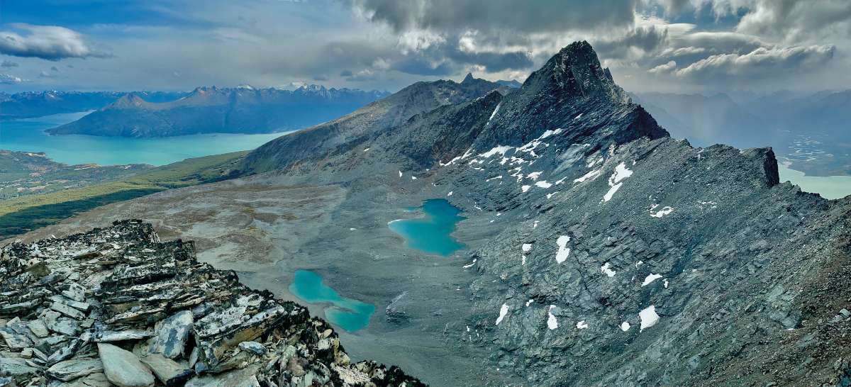 A Cóndor (1155 m) csúcspiramisán – Alattunk 300 m-rel munkahelyünk a hegyi tundrán, a nagy katlanban, amit még a 20. század közepén is jég töltött ki. Előttünk a Pirámide-vonulat gerincei és csúcsai, balra a Beagle-csatornából nyíló Yendegaia-öböl. Háttérben a Darwin-hegyvidék távoli szirtjei